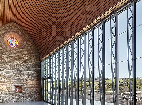 Die wärmegedämmte Vorhangfassade aus forster thermfix light Profilen mit integrierter Brandschutztür aus dem System forster fuego light öffnet den Blick über die grossartige Naturlandschaft. Die historische Kirche aus dem 13. Jahrhundert, Saint Christophe in Vachères in Frankreich, wird heute für Veranstaltungen, Konzerze und Ausstellungen genutzt.