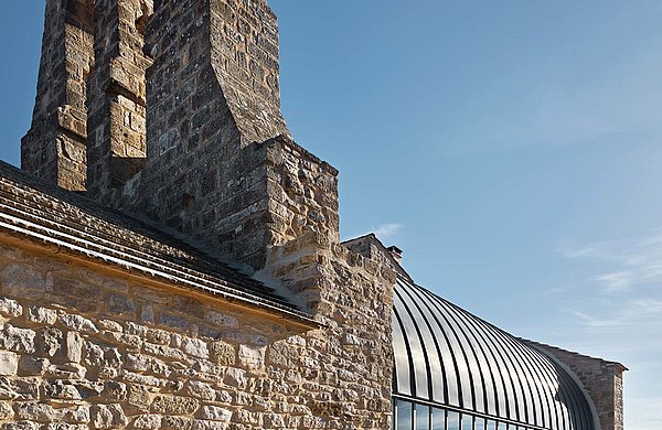 Restaurierung der Kirche Saint-Christophe in Vachères in Frankreich. Eine perfekte Verbindung von altem Gemäuer und modernem Aussehen. Die wärmegedämmte Vorhangfassade mit integrierter Brandschutztür bietet ein Maximum an Transparenz und natürlichem Lichteinfall. Verwendete Profilsysteme aus Stahl: forster thermfix light für die Fassade, forster fuego light für die Eingangstür.