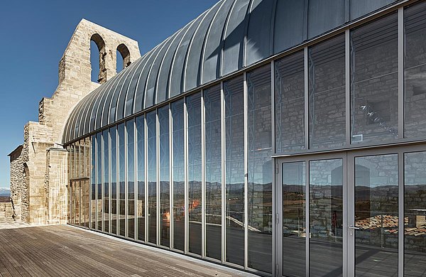 Thermally insulated curtain wall with integrated fire-rated door. Used steel profile systems: forster thermfix light for the curtain wall, forster fuego light for the entrance door. Historic church from the 13th century, Saint Christophe in Vachères, France.